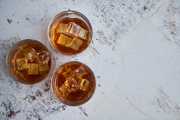 Image showing Three glasses filled with ice cubes and old aromatic whiskey