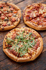 Image showing Composition of three various kinds pizzas on wooden table