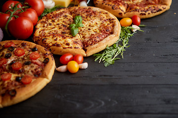 Image showing Freshly served, three various pizzas placed among tasty ingredients. Top view