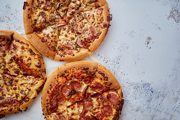 Image showing Three american style pizzas served on a table