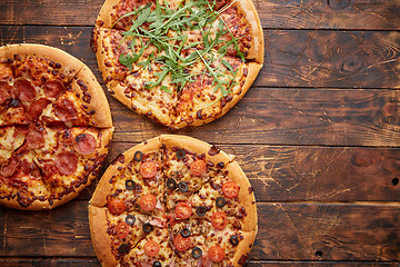 Image showing Composition of three various kinds pizzas on wooden table