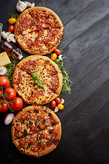 Image showing Freshly served, three various pizzas placed among tasty ingredie