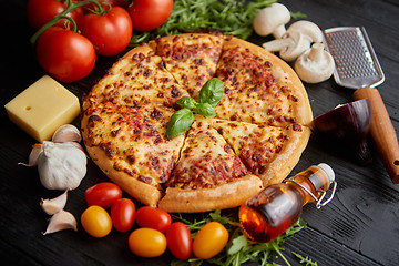 Image showing Delicious italian pizza served on black wooden table