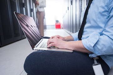 Image showing engineer working on a laptop in server room