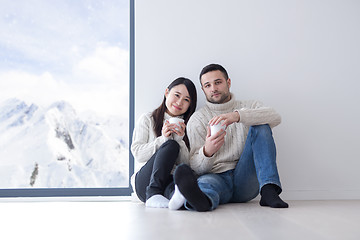 Image showing multiethnic couple enjoying morning coffee by the window