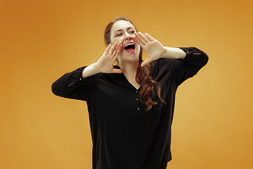 Image showing Isolated on orange young casual woman shouting at studio