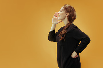 Image showing Isolated on blue young casual woman shouting at studio