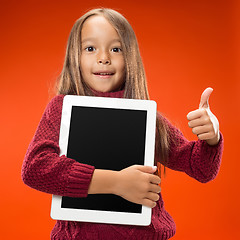 Image showing Little funny girl with tablet on studio background