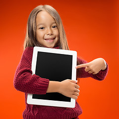 Image showing Little funny girl with tablet on studio background