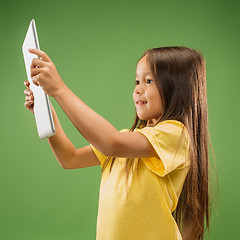 Image showing Teen girl with laptop. Love to computer concept. Attractive female half-length front portrait, trendy green studio backgroud.