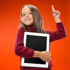 Image showing Little funny girl with tablet on studio background