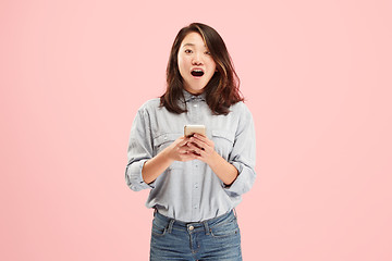 Image showing Young beautiful woman using mobile phone studio on pink color background