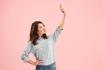 Image showing Portrait of a happy smiling casual girl showing blank screen mobile phone isolated over pink background