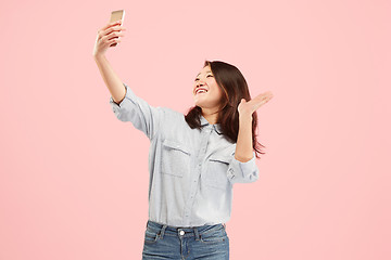 Image showing Portrait of a happy smiling casual girl showing blank screen mobile phone isolated over pink background