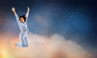 Image showing happy woman in blue pajama jumping over night sky