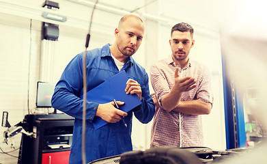 Image showing auto mechanic with clipboard and man at car shop