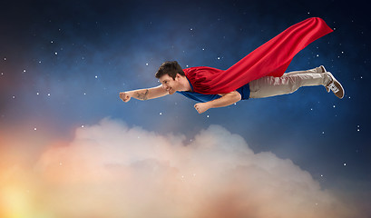 Image showing man in red superhero cape flying over night sky