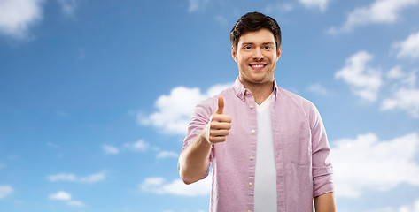 Image showing happy young man showing thumbs up over blue sky