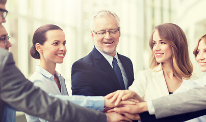 Image showing business people putting hands on top in office