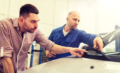 Image showing auto mechanic with clipboard and man at car shop