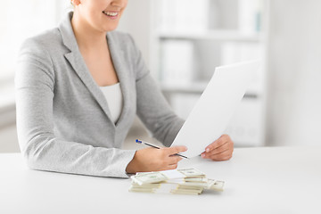 Image showing businesswoman with tax form and money on table