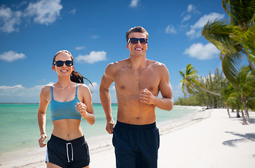 Image showing couple in sports clothes running along on beach