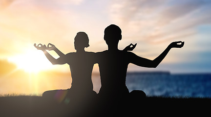 Image showing couple doing yoga in lotus pose over sunset