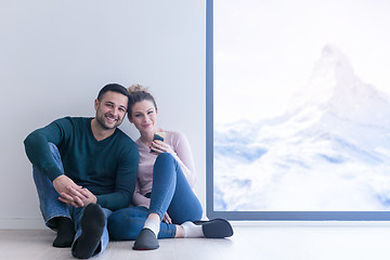 Image showing young couple sitting on the floor near window at home