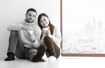 Image showing multiethnic couple enjoying morning coffee by the window