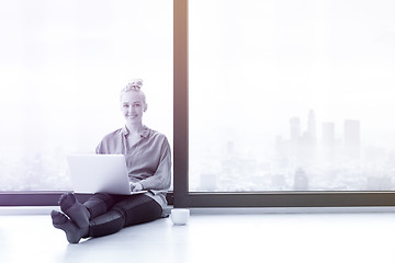 Image showing woman drinking coffee and using laptop at home