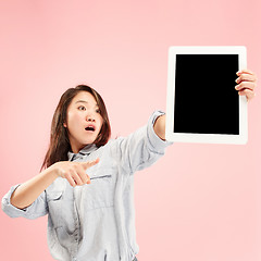 Image showing Portrait of a confident casual girl showing blank screen of laptop isolated over pink background