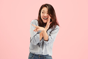 Image showing The young woman whispering a secret behind her hand over pink background