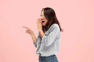 Image showing The young woman whispering a secret behind her hand over pink background