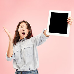 Image showing Portrait of a confident casual girl showing blank screen of laptop isolated over pink background