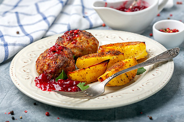 Image showing Meat cutlets are served with potatoes and lingonberry sauce.