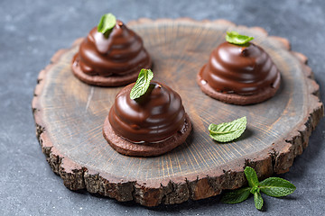 Image showing Chocolate mini cakes with green mint leaves.