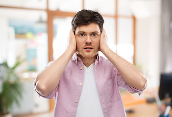 Image showing man closing ears by hands over office room