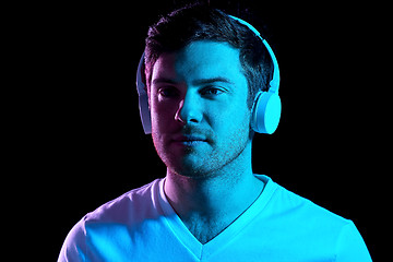 Image showing man in headphones over neon lights of night club