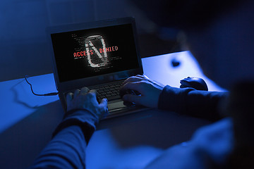 Image showing hands of hacker with access denied message laptop