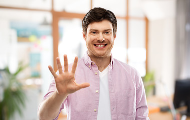 Image showing young man showing five fingers over office room