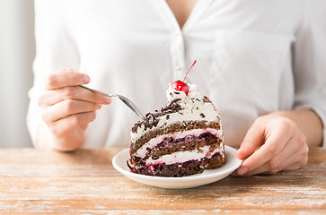 Image showing woman eating piece of layer cake with cherry