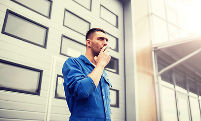 Image showing auto mechanic smoking cigarette at car workshop