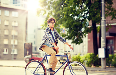 Image showing young hipster man with bag riding fixed gear bike