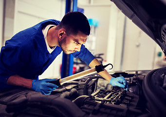 Image showing mechanic man with lamp repairing car at workshop