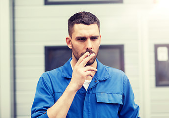 Image showing auto mechanic smoking cigarette at car workshop