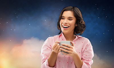 Image showing happy woman in pajama with mug of coffee at night