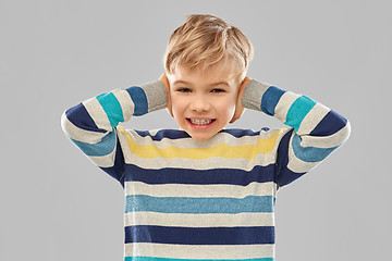 Image showing stressed boy in pullover closing ears by hands