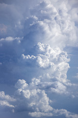 Image showing Vast blue sky with big white fluffy clouds lighted sun.