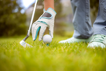 Image showing Hand in glove placing golf ball on tee