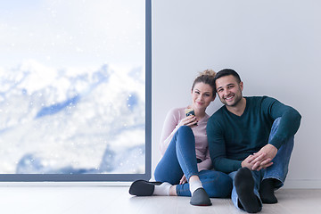 Image showing young couple sitting on the floor near window at home